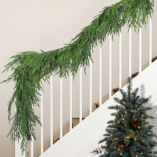 Green artificial pine garland draped along a staircase railing with needle tips.