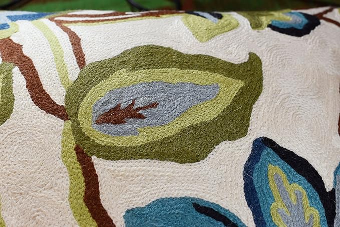 Close-up floral pillow cover with textured needlepoint cream background and blue tulip-like blooms
