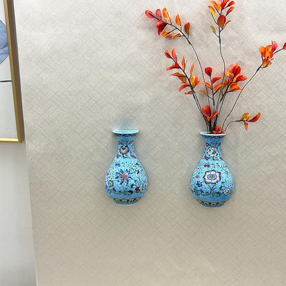 Two blue and white chinoiserie porcelain wall vases holding orange flowers