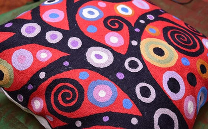 Red and black pillow cover with multicolor circular spirals and ring motifs.