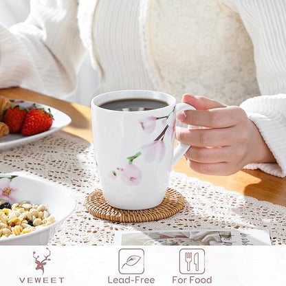 Floral ceramic coffee mug, white with pink blossoms, held by hand