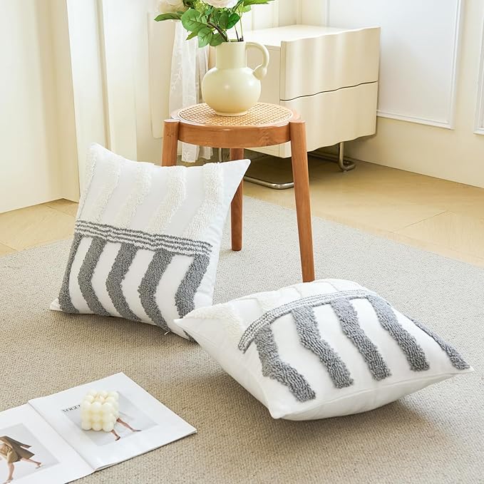 White pillow cover with gray arch stripe design, folded on sofa chair seat