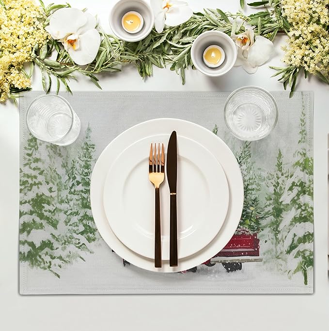 Set of four Christmas placemats; one shows red truck, pine branches, snowy landscape