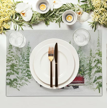 Set of four Christmas placemats; one shows red truck, pine branches, snowy landscape