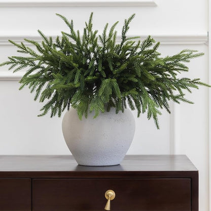 Artificial green Norfolk pine branch in a white speckled pot with dense needles