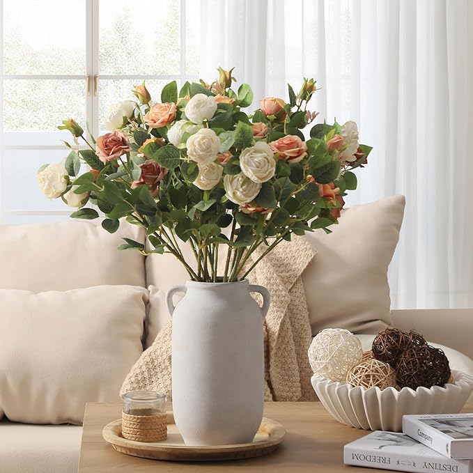 White ceramic vase with side handles holding mixed rose flowers and greenery