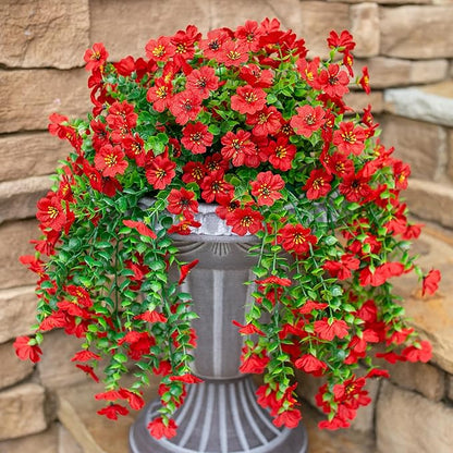 Red faux hanging flowers and green vines cascading over gray planter