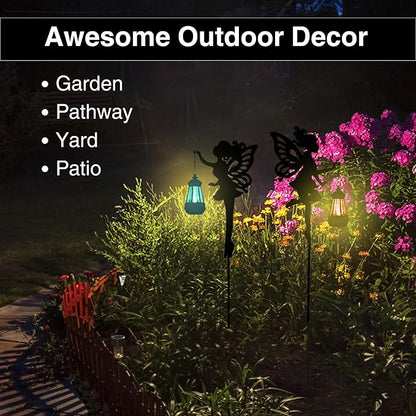 Pair of black fairy yard stake solar lanterns in blooming garden beds at night