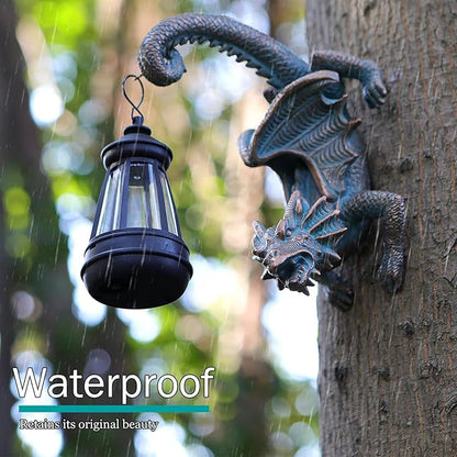 Outdoor dragon tree hugger statue beside black solar lantern, dark green-blue dragon wings