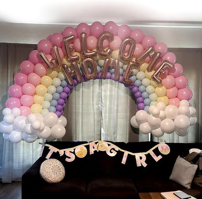 Rainbow balloon arch with pink, purple, yellow, blue, and white balloons and gold balloon letters