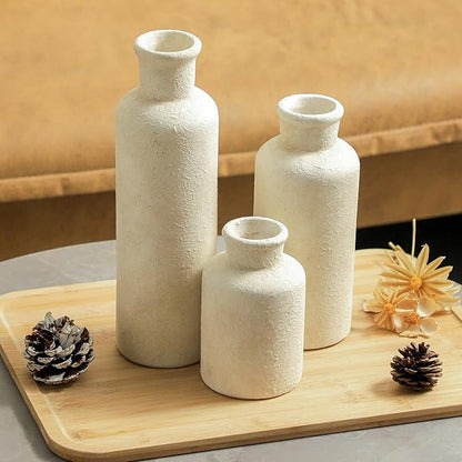 Three whitewashed terracotta ceramic vases with rounded shoulders and narrow mouths
