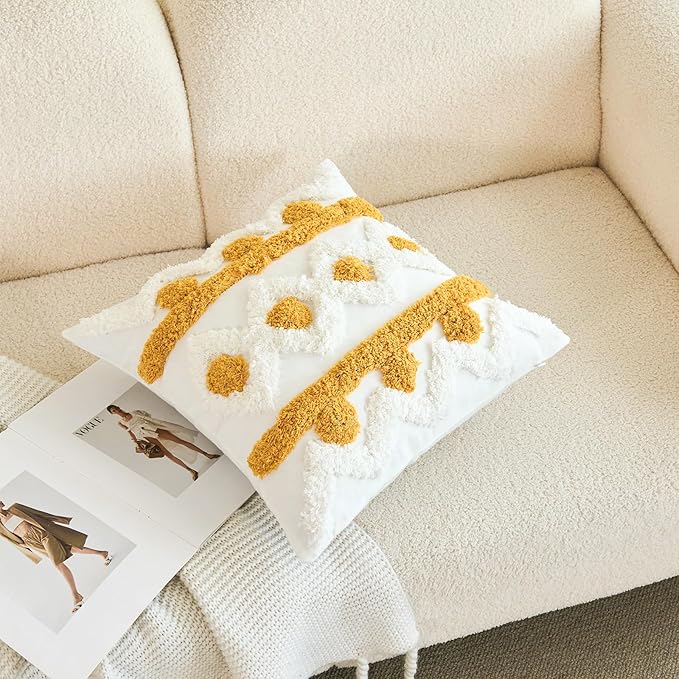 White pillow cover with gold tufted dots and fringe-like yarn edging, laid on couch