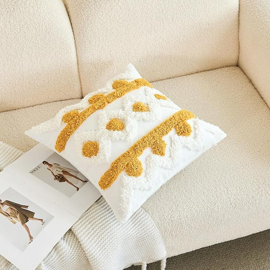White pillow cover with gold tufted dots and fringe-like yarn edging, laid on couch