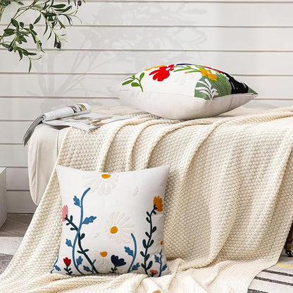 White square pillow cover with colorful daisy and vine embroidery with red accents