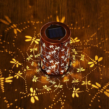 Brown solar lantern with white dragonfly and floral design, emitting warm glowing light