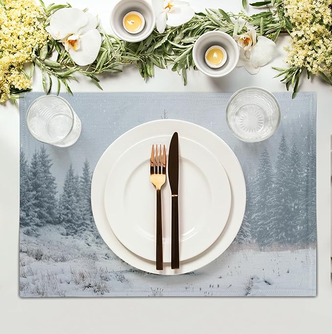 Winter table placemat with snowy pine forest print, placed under white dinner plates.