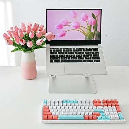Light pink faux tulip bouquet in gradient pink vase beside a laptop keyboard