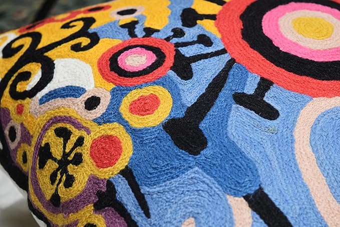 Embroidered decorative pillow cover with abstract floral-like and ring motifs in yellow, blue, and red.