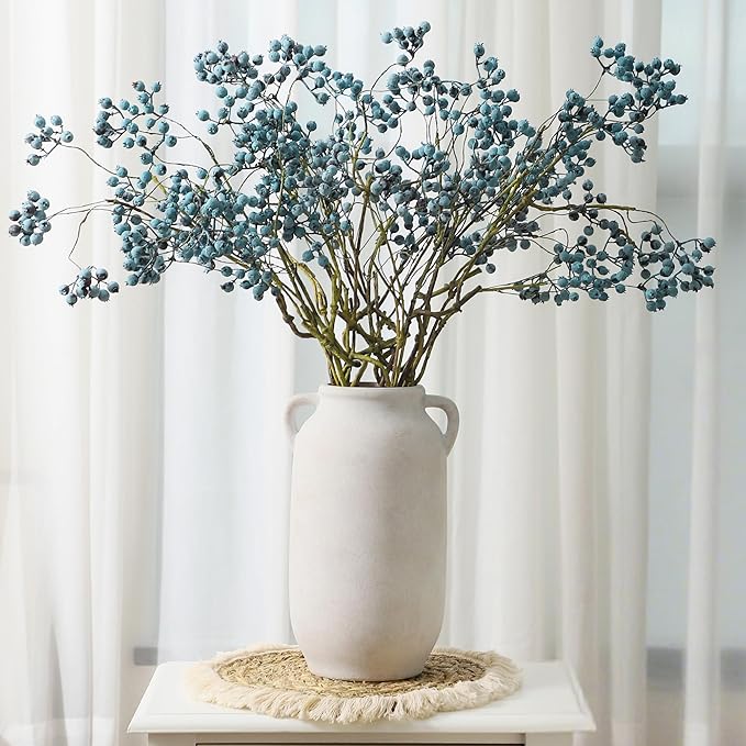 White ceramic vase with side handles holding blue-green eucalyptus stems