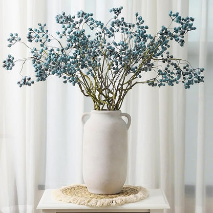 White ceramic vase with side handles holding blue-green eucalyptus stems