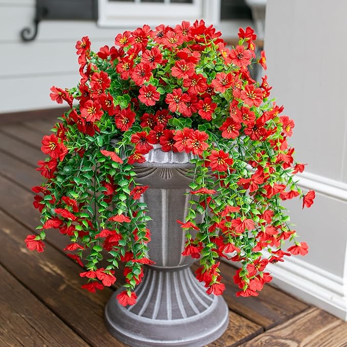 Red faux hanging flower bundles with green trailing vines over gray metal planter