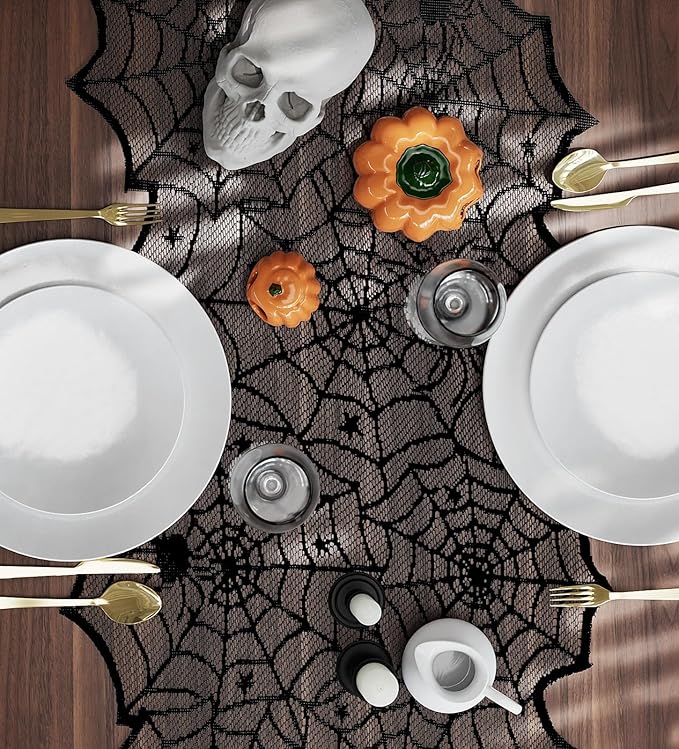 Black spiderweb lace table runner laid on table with plates and pumpkin decor