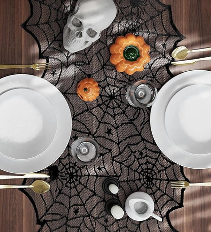 Black spiderweb lace table runner laid on table with plates and pumpkin decor