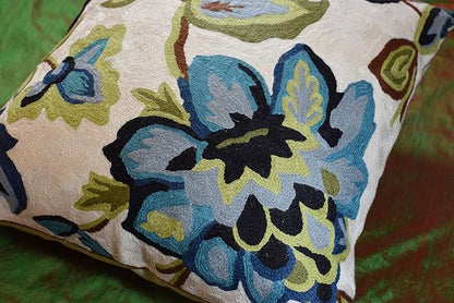 Cream floral cushion cover with embroidered blue flowers and green leaves, textured surface