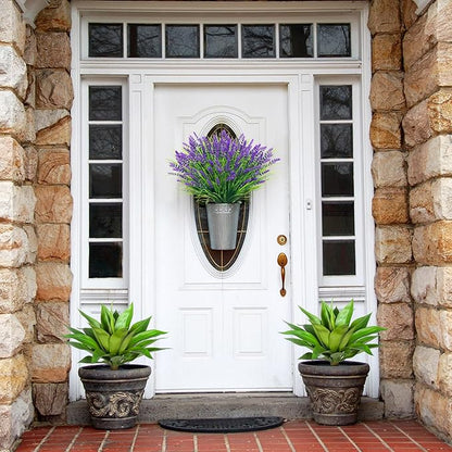 Two faux agave plants in dark pots on a porch walkway