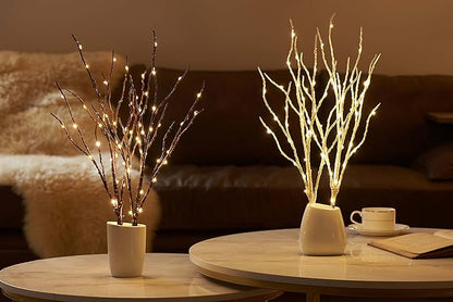 Two brown lighted willow branches in pots with warm white LED glow on table