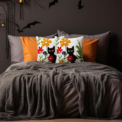 Embroidered pillow cover with black cat and colorful blooms on a white background
