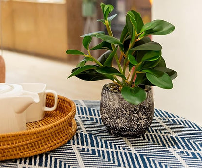 Faux ficus plant in speckled black cement planter on patterned rug