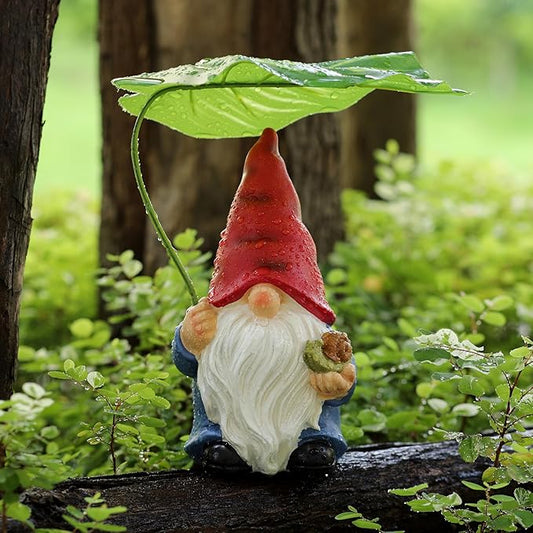 Garden gnome statue with green leaf umbrella, red hat, white beard, blue outfit on stone.