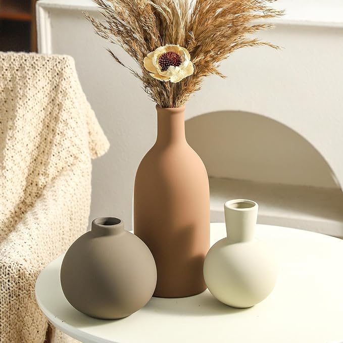 Ceramic vase set with terracotta, taupe, and white vases holding dried stems
