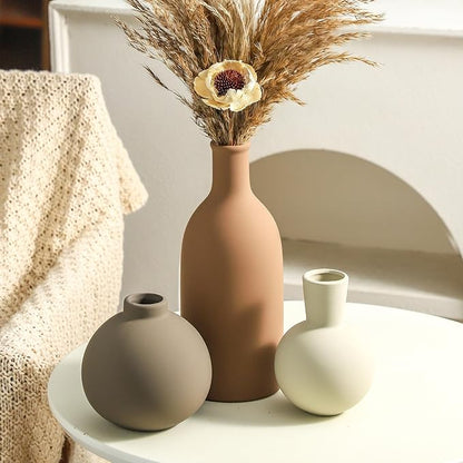 Ceramic vase set with terracotta, taupe, and white vases holding dried stems