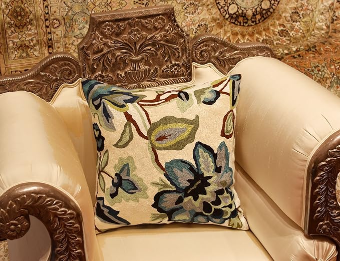 Floral pillow cover in cream with embroidered blue and green blossoms on chair