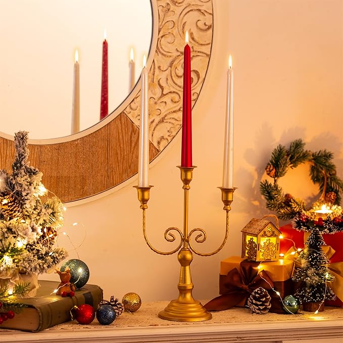 Two gold three-stem taper candle holders with curled scroll arms on a round pedestal base
