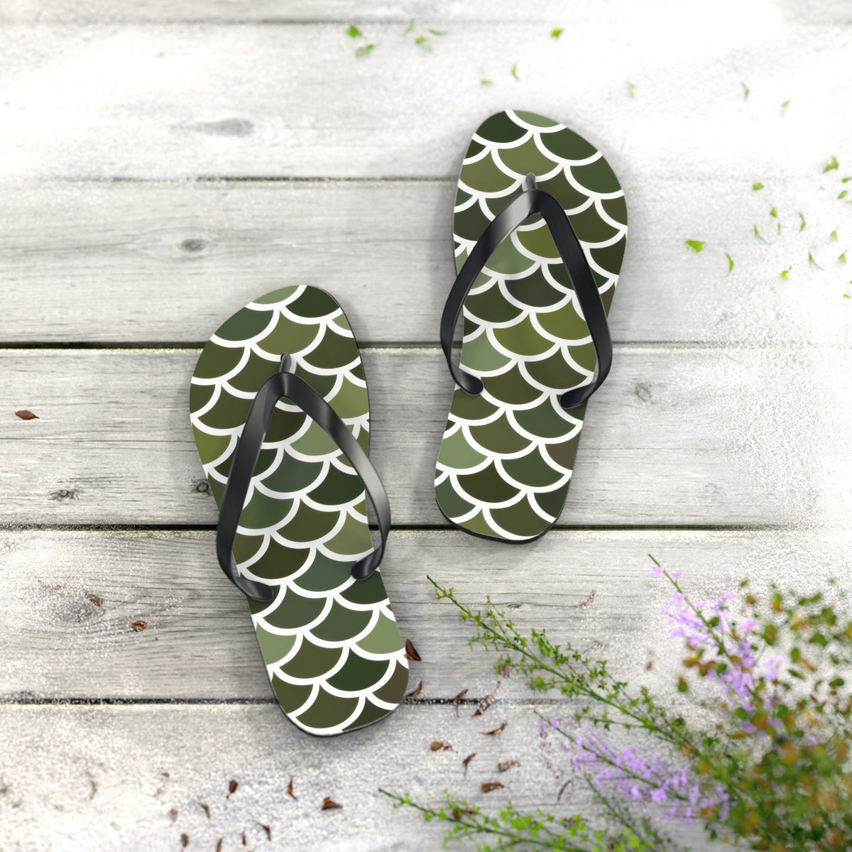 Pair of green scale print flip flops with black straps on textured surface