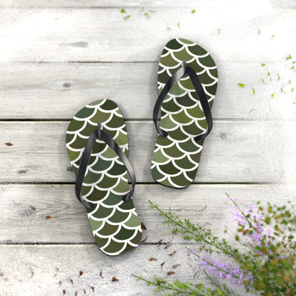 Pair of green scale print flip flops with black straps on textured surface