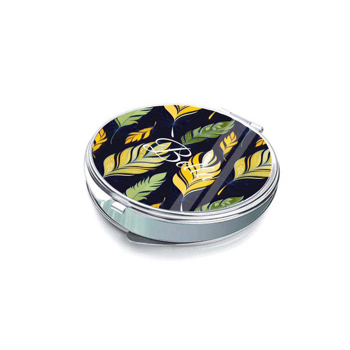 Low-angle view of a feather-patterned round compact mirror with silver sides