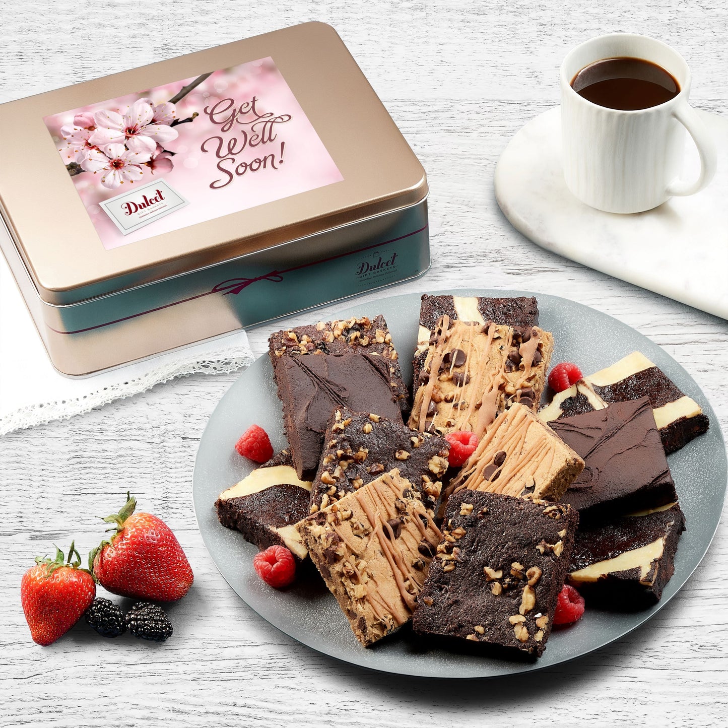 Assorted brownie gift tin with sliced chocolate brownies on a plate and strawberries