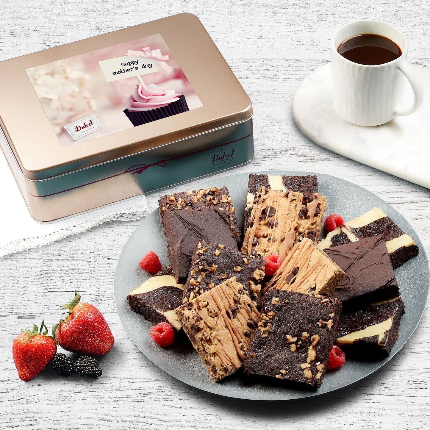 Assorted brownie gift tin with sliced chocolate brownies on a plate and strawberries