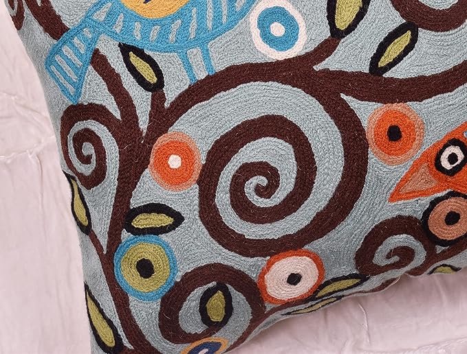 Embroidered bird and spiral pattern on teal blue pillow cover edge