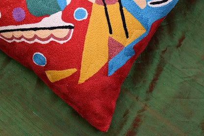 Red abstract pillow cover fabric close-up with multicolor shapes along the edge