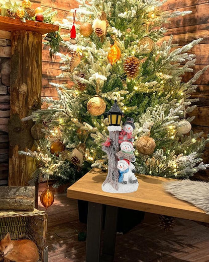 Lighted stacked snowman lantern decor displayed on wooden table near Christmas tree