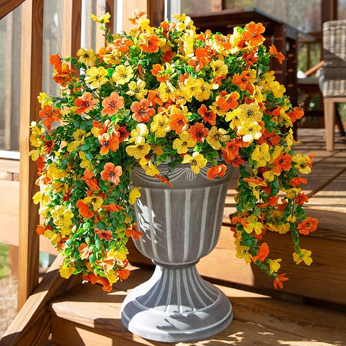 Artificial flower bundle with orange and yellow blossoms and long trailing green leaves