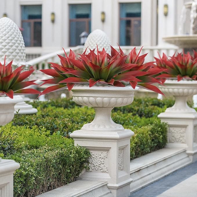 Wine-red faux agave plant with green centers on white pedestal planter