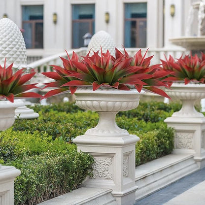 Wine-red faux agave plant with green centers on white pedestal planter