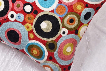 Red pillow cover with multicolor circular pattern, styled on white bedding