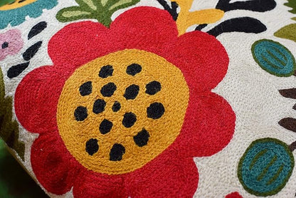 Close-up of a large red embroidered flower with a yellow center on the pillow cover.